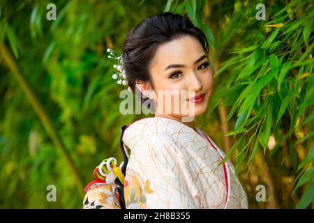 Portrait d'une femme souriante portant un kimono debout dans le parc Banque D'Images