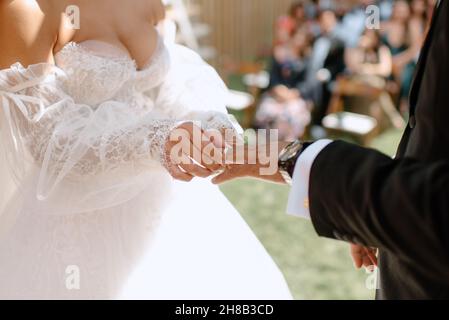 Gros plan de la mariée mettant l'anneau de mariage sur le doigt de marié Banque D'Images