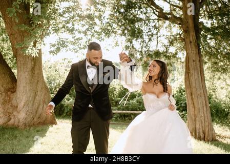 Une mariée souriante et un marié dansant dans le parc Banque D'Images