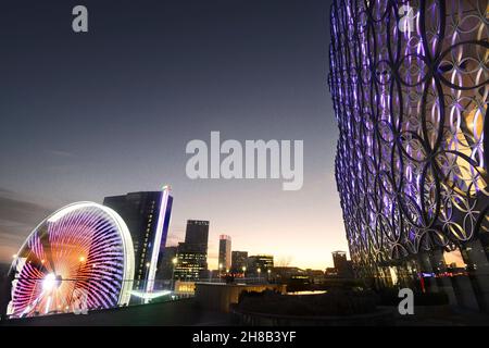 Architecture complexe de la façade de la bibliothèque, bâtiments illuminés du centre-ville et tours du parc des expositions de Noël en contrebas, au crépuscule sur un hiver fin Banque D'Images
