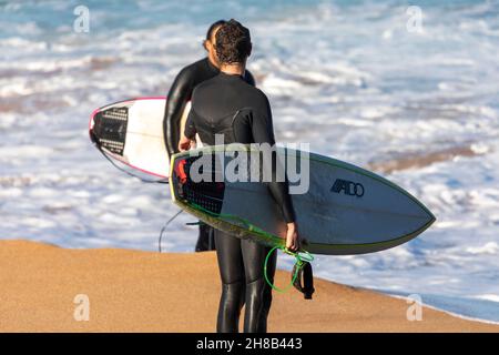 Deux surfeurs adultes mâles I wetsues sur la plage se préparant à aller surfer, Sydney, Australie Banque D'Images
