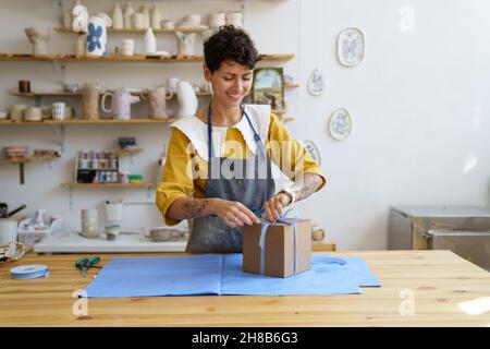 Vendeur féminin dans la vaisselle artisanale et la poterie artisanale emballage et décorer boîte cadeau pour le client Banque D'Images