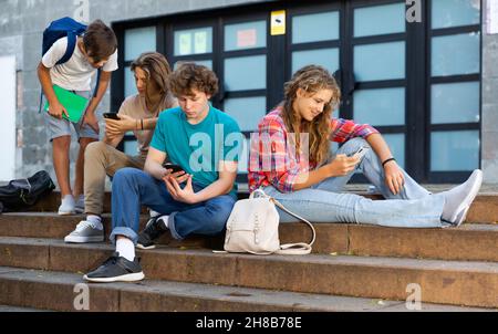 Les écoliers utilisent des gadgets en pause à l'extérieur de l'université Banque D'Images