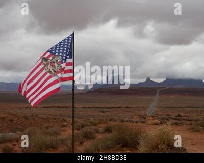 Drapeau américain avec un amérindien à cheval avec une vallée et des montagnes dans Monument Valley en arrière-plan.Ciel nuageux au-dessus. Banque D'Images