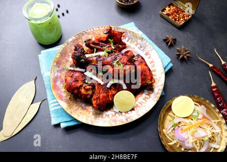 Le poulet Tandoori est une recette populaire de poulet rôti de l'Inde.Tandoor est un four traditionnel en bois.Le plat de poulet Tandoori est servi dans une assiette noire Banque D'Images