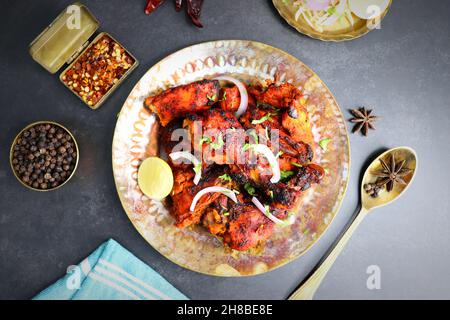 Le poulet Tandoori est une recette populaire de poulet rôti de l'Inde.Tandoor est un four traditionnel en bois.Le plat de poulet Tandoori est servi dans une assiette noire Banque D'Images