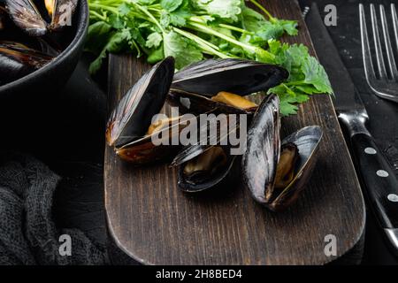 Moules cuites avec sauce au fromage et sauce à l'ail, dans un bol, sur fond noir Banque D'Images