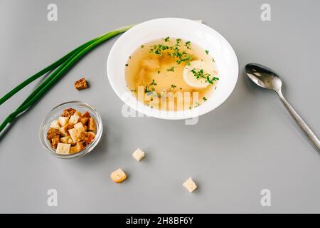 Soupe de nouilles de poulet avec œuf dans une assiette blanche.Cuillère, oignon vert et craquelins autour de l'assiette. Banque D'Images