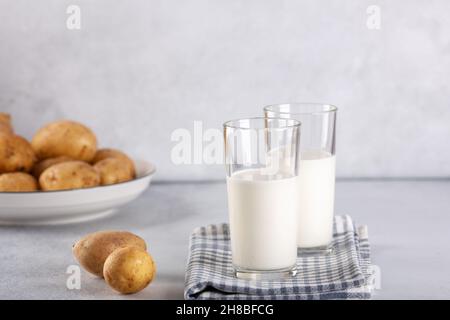 Boisson de pomme de terre sans lait dans des verres.Lait de pomme de terre de remplacement et tubercules de pomme de terre sur table grise.Espace de copie - image Banque D'Images