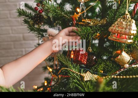 Magnifique arbre de Noël décoré sur fond de mur en brique blanche.Boules suspendues à la main pour enfants. Banque D'Images