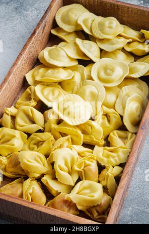 Tortellini et Ravioli faits main à l'italienne, en boîte de bois, sur fond gris Banque D'Images