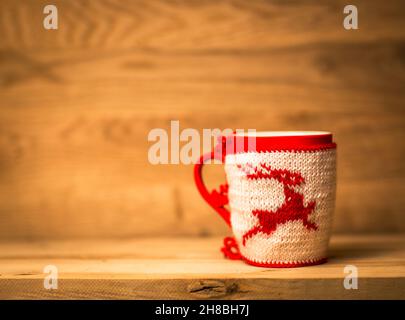 mug en laine isolante avec cerf brodé sur la table en bois Banque D'Images