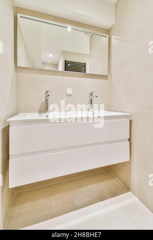 Lavabo coûteux en pierre naturelle avec robinet blanc sous miroir dans la salle de bains Banque D'Images