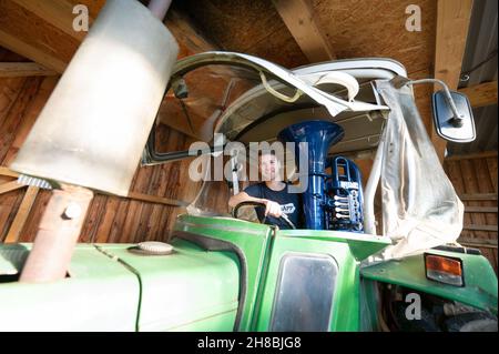 Brackenheim, Allemagne.23 novembre 2021.Micha, de Brackenheim, un musicien portant le nom de scène « Micha von der Rampe », est assis avec son tuba bleu sur un tracteur.Il a raccroché un emploi dans la banque pour sa musique.Au lieu de porter un costume, il vient maintenant dans un pantalon en cuir et apporte une bouffée d'air frais dans la scène pop avec son tuba bleu.Credit: Marijan Murat/dpa/Alamy Live News Banque D'Images