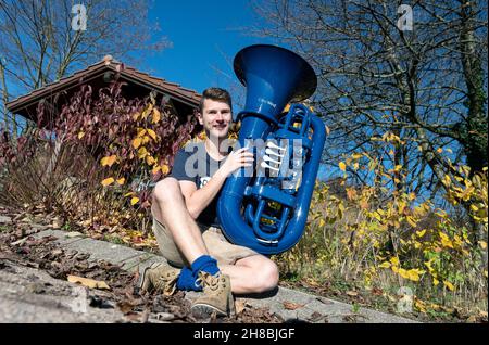 Brackenheim, Allemagne.23 novembre 2021.Micha, de Brackenheim, musicien portant le nom de scène 'Micha von der Rampe', se trouve sur le côté de la route avec son tuba bleu.Il a cédé un emploi à la banque pour sa musique.Au lieu de porter un costume, il porte maintenant un pantalon en cuir et apporte une bouffée d'air frais à la scène pop avec son tuba bleu.(À dpa Un banquier avec un tuba bleu lors d'une visite du village) Credit: Marijan Murat/dpa/Alamy Live News Banque D'Images