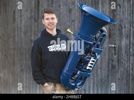 Brackenheim, Allemagne.23 novembre 2021.Micha, de Brackenheim, musicien portant le nom de scène 'Micha von der Rampe', tient son tuba bleu.Il a raccroché un emploi dans la banque pour sa musique.Au lieu de porter un costume, il vient maintenant dans un pantalon en cuir et apporte une bouffée d'air frais dans la scène pop avec son tuba bleu.Credit: Marijan Murat/dpa/Alamy Live News Banque D'Images