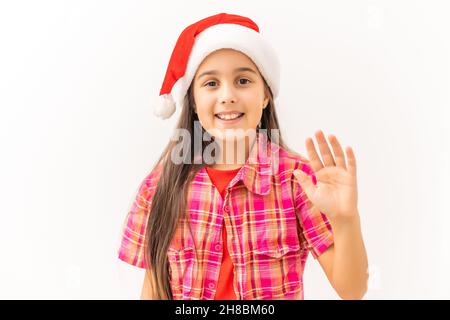 La fille regarde l'appareil photo.Elle sourit un large sourire.S la fille porte un chapeau de Père Noël.Rien ne se passe sur fond blanc Banque D'Images