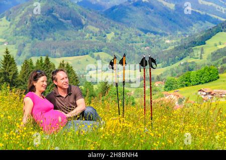 Les parents enceintes se détendent dans un pré de fleurs Banque D'Images