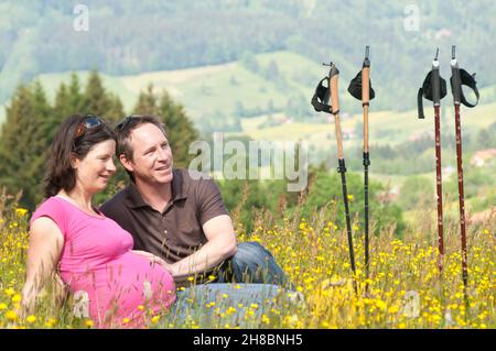 Les parents enceintes se détendent dans un pré de fleurs Banque D'Images