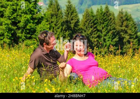 Les parents enceintes se détendent dans un pré de fleurs Banque D'Images