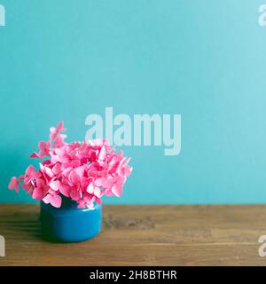 Vase de fleurs d'hortensia rose sur table en bois. Fond de mur bleu menthe. Intérieur de la maison Banque D'Images