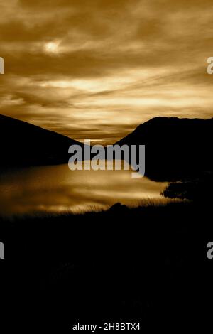 Llyn Pen-y-Gwryd au coucher du soleil, avec des nuages et des montagnes reflétés dans l'eau.Partie du parc national de Snowdonia Banque D'Images