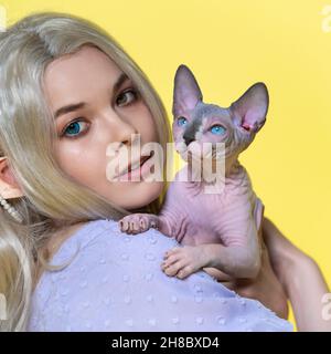 Portrait de jeune femme cosplay elf tenant le chaton Sphinx entre les mains, souriant et regardant l'appareil photo avec des yeux de différentes couleurs.L'elf a des cheveux blonds Banque D'Images