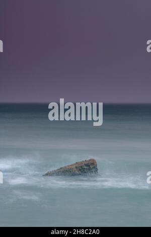 roche isolée unique en mer avec ciel sombre et atmosphère, paysage marin sombre avec roche et mer laiteuse tourbillonnante comme la brume. Banque D'Images