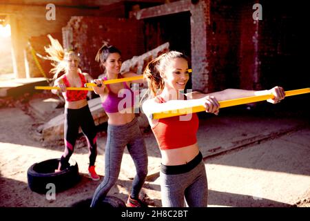 Groupe de personnes de forme physique sautant courir avec le bâton jaune.Amis s'exerçant à l'extérieur de l'énergie positive lumineuse. Banque D'Images