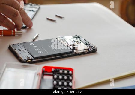 Smartphone démonté, outils à main et pièces sur une surface légère.Réparation des services.Mise au point sélective. Banque D'Images