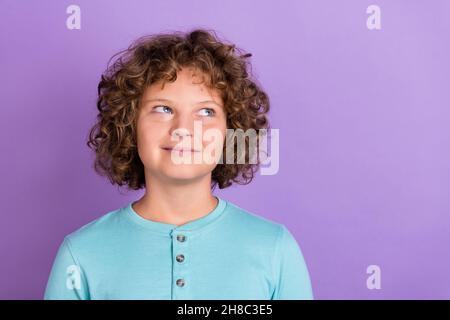 Portrait d'une jolie tricherie pensive, un garçon aux cheveux ondulés surpensant un espace de copie isolé sur fond violet vif de couleur violet Banque D'Images