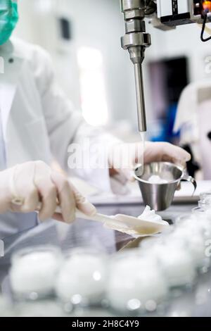 Mains de sexe masculin en manteau blanc et gants de préparation de la crème.Préparation de crème pour les mains.Soins de beauté Banque D'Images