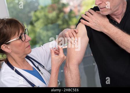 Femme médecin vaccinant un homme âgé Banque D'Images