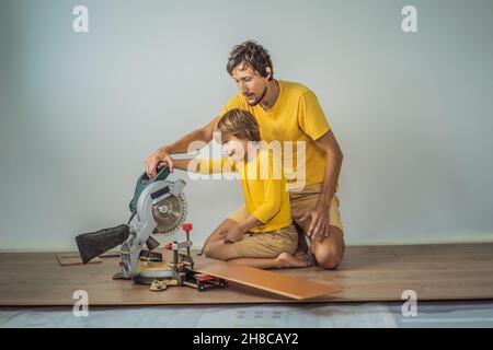 Père et fils installant un nouveau parquet stratifié en bois sur un plancher de film chaud.Système de chauffage au sol infrarouge sous sol stratifié Banque D'Images