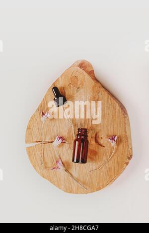 Laboratoire cosmétique abstrait.Bouteilles de verre ambré foncé sur un podium en bois.Cosmétiques naturels.Style plat, vue de dessus. Banque D'Images