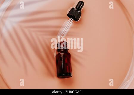 Laboratoire cosmétique abstrait.Flacons en verre ambré foncé sur fond liquide beige.Cosmétiques naturels pour les soins, homéopathie.Style plat, vue de dessus. Banque D'Images