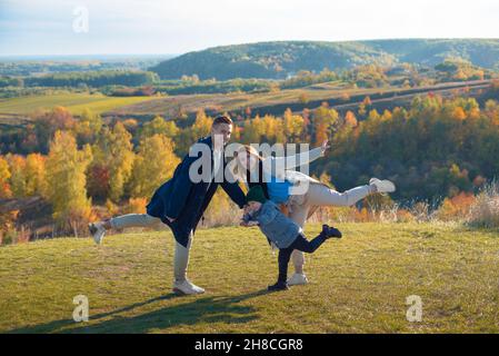 Jeunes parents caucasiens s'amusant avec leur fils sur une colline en plein air temps d'automne Banque D'Images