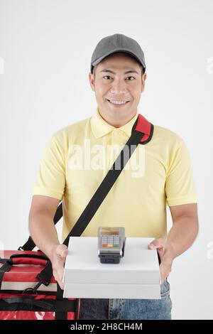 Portrait d'un beau coursier souriant donnant des boîtes de pizza et le terminal de paiement acceptant le paiement pour la livraison Banque D'Images