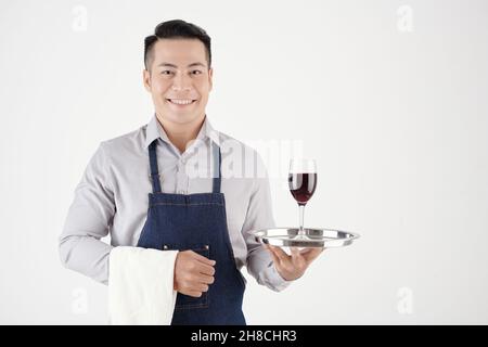 Serveur de restaurant gai avec une serviette blanche et un plateau avec un verre de vin Banque D'Images