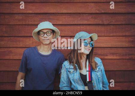 couples asiatiques portant des vêtements chapeau et style de vie décontracté debout contre un mur en bois Banque D'Images