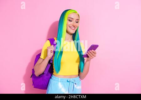 Photo d'une jeune femme souriante étudiant à l'université en utilisant un smartphone isolé sur fond de couleur rose Banque D'Images