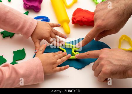 Fille jouant de la pâte avec son père. Fille père jouant au jeu sur fond blanc.Faire différentes formes avec de la pâte.Gros plan.Fête des pères Banque D'Images