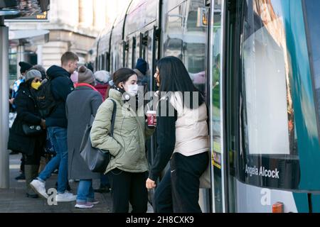 Les gens défont un tramway à Nottingham, la ville où l'un des deux cas de la variante Omicron de Covid-19 a été identifié la semaine dernière. Banque D'Images