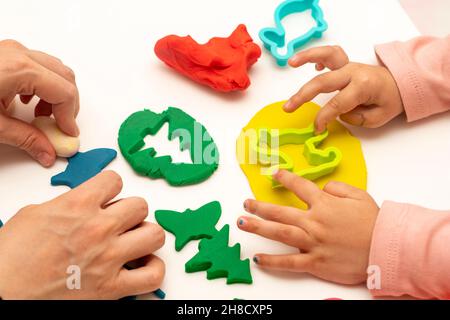 Fille jouant de la pâte avec sa mère. Mère et fille jouant sur un fond blanc.Faire différentes formes avec de la pâte.Gros plan.Fête des mères Banque D'Images