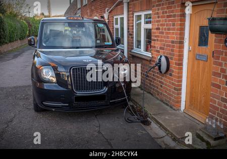 Thaxted Essex UK Electric London taxi chargement novembre 2021 Electric London taxi chargement à un point de chraring électrique fixé au mur de h privé Banque D'Images