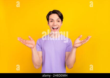 Photo d'étonnant drôle gentil gars bouche ouverte wow réaction porter violet t-shirt isolé couleur jaune fond Banque D'Images