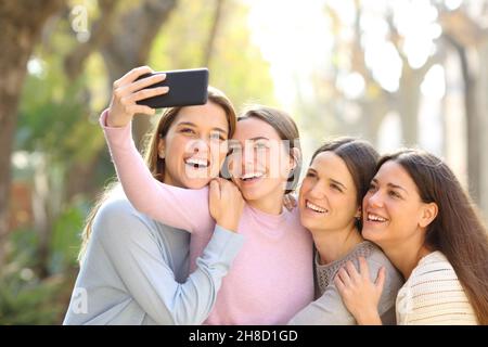 Quatre amis heureux prenant des selfies avec un smartphone dans la rue Banque D'Images