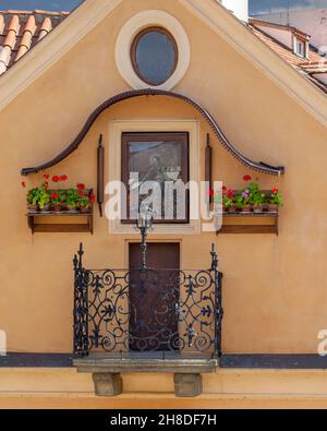 Un sanctuaire coloré de la Vierge à l'enfant au-dessus d'un balcon en fer forgé sur un bâtiment ocre dans la vieille ville de Prague Banque D'Images