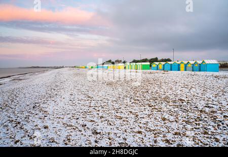 Des cabanes de plage et la plage couverte d'une fine couche de neige en hiver à Littlehampton, West Sussex, Angleterre, Royaume-Uni. Banque D'Images