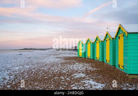 Des cabanes de plage et la plage couverte d'une fine couche de neige en hiver à Littlehampton, West Sussex, Angleterre, Royaume-Uni. Banque D'Images